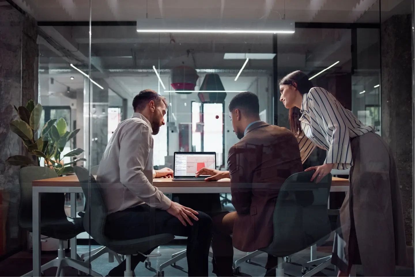Three construction professionals reviewing a BIM model in the Solibri interface on a laptop, representing collaborative model validation to help prevent commissioning delays in data center projects.